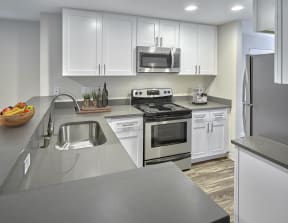Updated kitchen with stainless steel appliances, white cabinets, and grey countertops.
