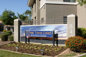 a sign in front of an apartment building with a sunset in the background