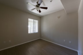 an empty bedroom with a ceiling fan and a window