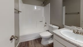 Ontario CA Apartments - Rancho Vista - Bathroom With a Toilet and Shower, a Towel Rack, and a Sink With a Mirror