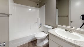 Ontario CA Apartments for Rent - Rancho Vista - Bathroom With a Large Mirror, Wood Styled Flooring, and a Toilet With an adjacent Shower