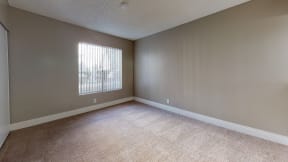 Apartments in Ontario- Avante Apartments Bedroom with Wall to-Wall Carpet and A Large Window