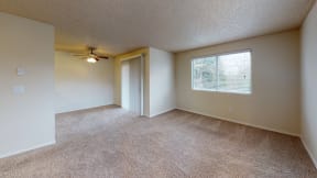 Apartments in Ontario for Rent - Encore Apartment Homes - Spacious Living Room with Plush Carpeting, a Ceiling Fan, Large Window, and Access to the Patio