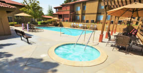 The Arches at Regional Center West Apartments in Antelope Valley, CA - Sparkling Swimming Pool and Spa Surrounded by Lounge Chairs with Covered Tables