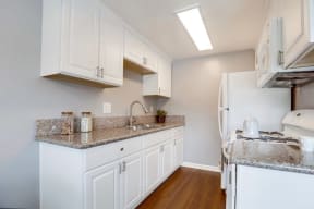 Apartments for Rent West Covina - Tuscany Villas - Updated Kitchen with White Cabinets, Granite Countertops, Wood-Style Flooring, and White Appliances