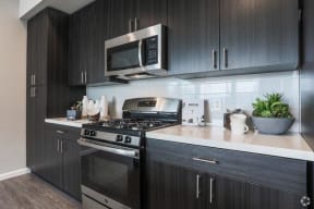 kitchen with dark wood cabinets, white quartz countertops and stainless and black appliances
