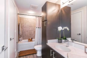 bathroom with espresso cabinets, white countertops and bath shower combo