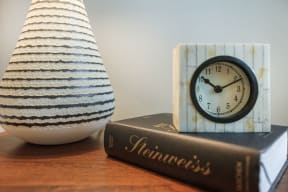 bedside table with book, clock and vase