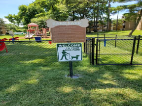 a sign in front of a park with a playground in the background