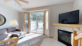 Bright and airy living space with a stone fireplace, French doors, and a private patio.