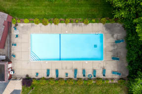 Aerial image of the outdoor pool, sundeck with lounge chairs, and surrounding lush lawn.