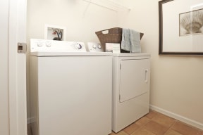 In home washer and dryer side by side with storage shelf above.