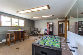 Community game room features foosball table, vending machine, and options for seating.