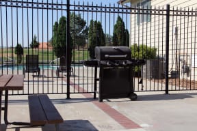 Community grilling area near pool separated by a black iron fence.