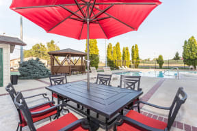 Outdoor patio table with umbrella on the pool deck for lounging in the sun or shade.