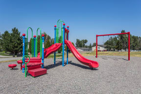 Red and blue community playground with slides and swings to play on.