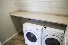 In unit washer and dryer side by side with a countertop perfect for laundry as well as shelf storage above.