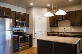 Updated kitchen with stainless steel appliances, wood cabinets, and island for entertaining.