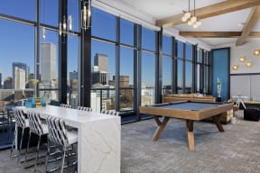 Sky lounge with granite table, pool table and large glass windows with view of Denver skyline