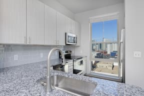 Kitchen with white cabinets, stainless steel appliances and granite countertops, window with skyline view