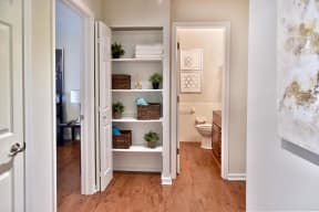 All white hallway with extra large closets for storage in between bedroom and private bathroom.