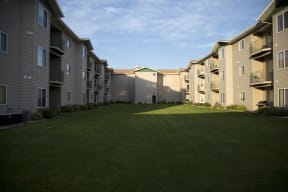Lush grounds of Cottonwood Apartment Homes with sunlight shining on the patio and balconies.