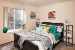 Bright and cozy bedroom with ample natural light coming in from the window across from the bed.