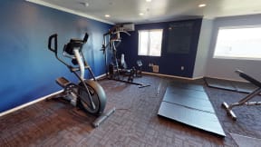 On site fitness center with a variety of  machine and equipment options against a blue wall.