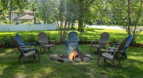 Outdoor firepit area with lawn chairs and plenty of green space.