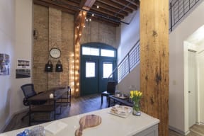 View of entryway from kitchen. Shows wood bean, exposed brick, and iron staircase.