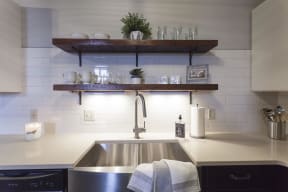 Exposed open shelving above large sink with stainless steel finishes.