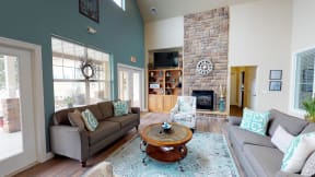 Relaxing community space with a floor to ceiling fireplace, teal accent wall, and comfortable furnishings.