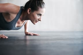 A woman working out in a fitness center by doing a push up.