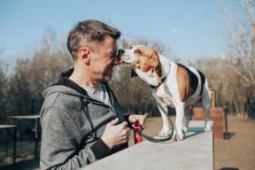 Image of a man and his Beagle dog smiling happily. We are a pet friendly community with a dog park.