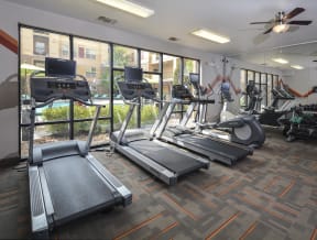Fitness Center complete with treadmills and other equipment placed by large windows that look out into the pool and picnic area.