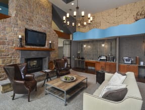 Clubhouse furnished with cozy couches, a stone fireplace, TV, and Coffee Bar.