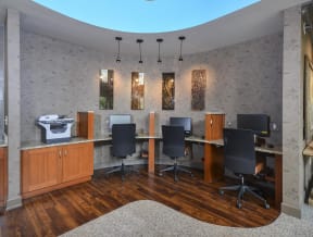On site business center with a printer and three individual workstations equipped with desk chairs and monitors.