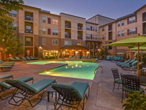 Gorgeous outdoor pool area with a heated pool, lounging chairs, and umbrella patio tables.