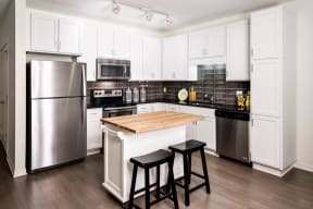 Kitchen with small central island, white cabinets finishes and stainless steel appliances