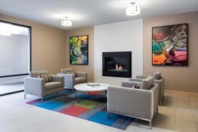 Community space with four armchairs surrounding small table, fireplace in the wall