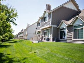 Exterior of Cascade Shores Townhome, the townhome has gray siding and white trim. Behind the townhome is a large lawn of lush green grass.