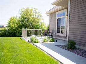 Private patio at Cascade Shores Townhomes with a paved walkway and a lush lawn.