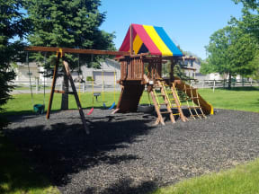 Outdoor community playground with swing set and ample green space.
