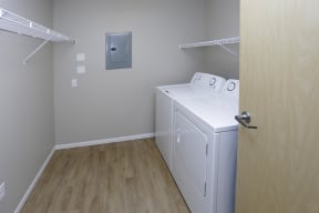 In unit washer and dryer located in the walk-in closet with storage shelves and hanging space.