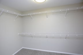 Inside of spacious walk in closet with plenty of shelves and hanging space.