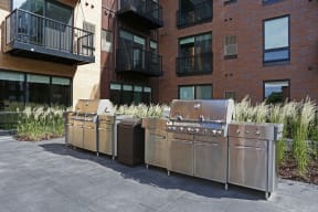 Outdoor grilling station with the exterior brick of Oxbo Urban Rentals behind.