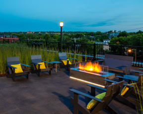 Outdoor fireplace at night with lounge chairs all looking out onto gorgeous St. Paul.