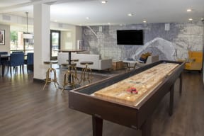 Large, bright clubroom complete with entertaining bar, shuffleboard, and TV lounge area with large glass doors looking out into the pool deck.