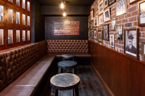 Private clubroom styled as a speakeasy with leather booths and brick gallery wall.