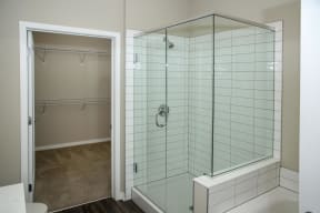 Spacious bathroom with a tiled shower enclosed by glass next to a walk in shower.